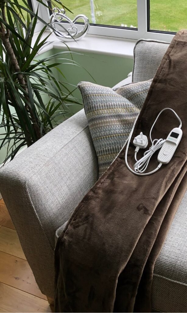 CoziPlus Classic heated throw in brown draped over a sofa