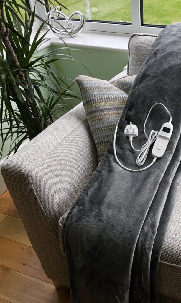 CoziPlus Classic heated throw in grey draped over a sofa