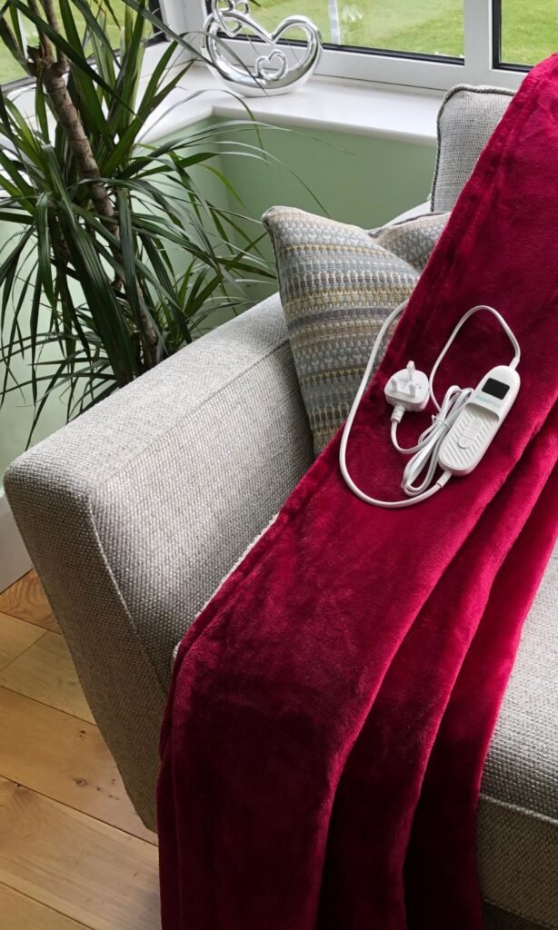 CoziPlus Classic heated throw in raspberry red draped over a sofa