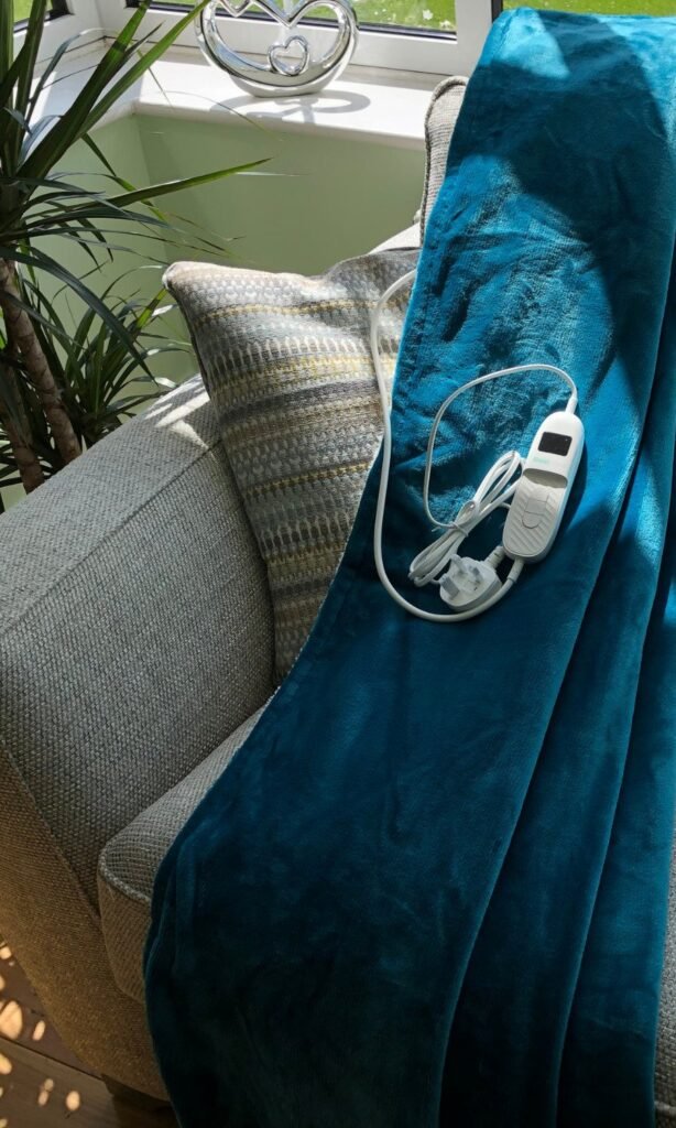 CoziPlus Classic heated throw in teal draped over a sofa