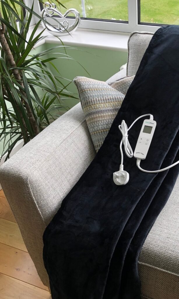 CoziPlus Premium heated throw in black draped over a sofa