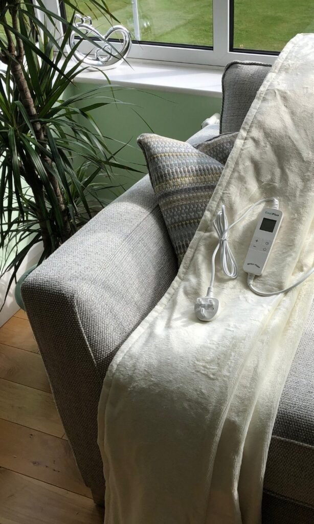 CoziPlus Premium heated throw in cream draped over a sofa