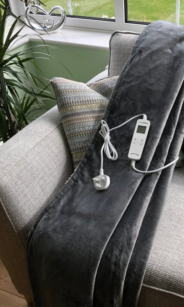 CoziPlus Premium heated throw in grey draped over a sofa