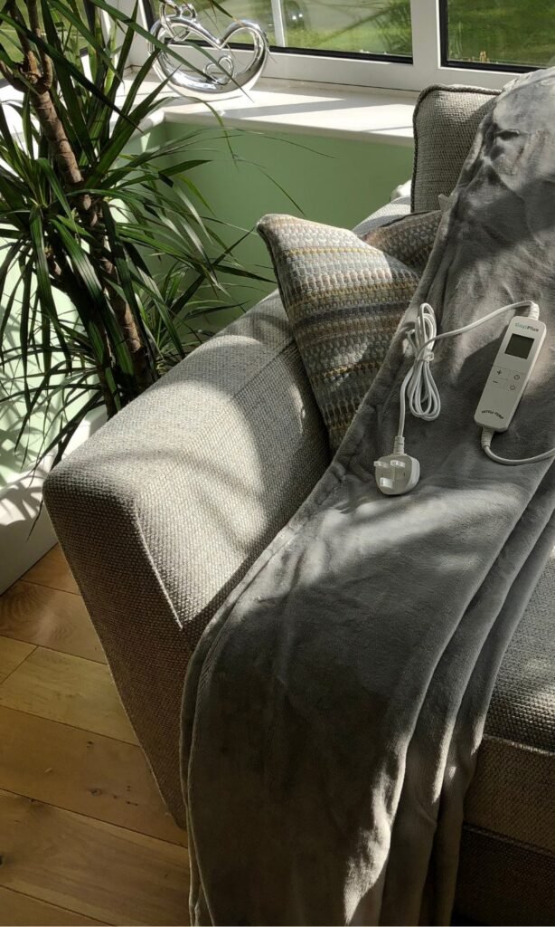 CoziPlus Premium heated throw in light grey draped over a sofa