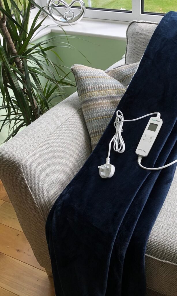 CoziPlus Premium heated throw in navy draped over a sofa