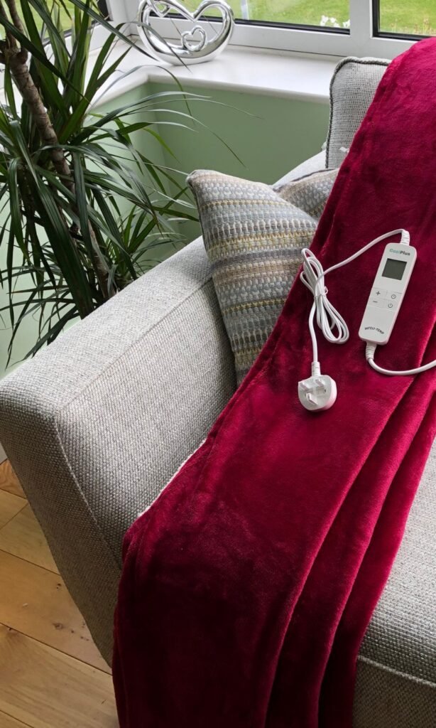 CoziPlus Premium heated throw in raspberry red draped over a sofa