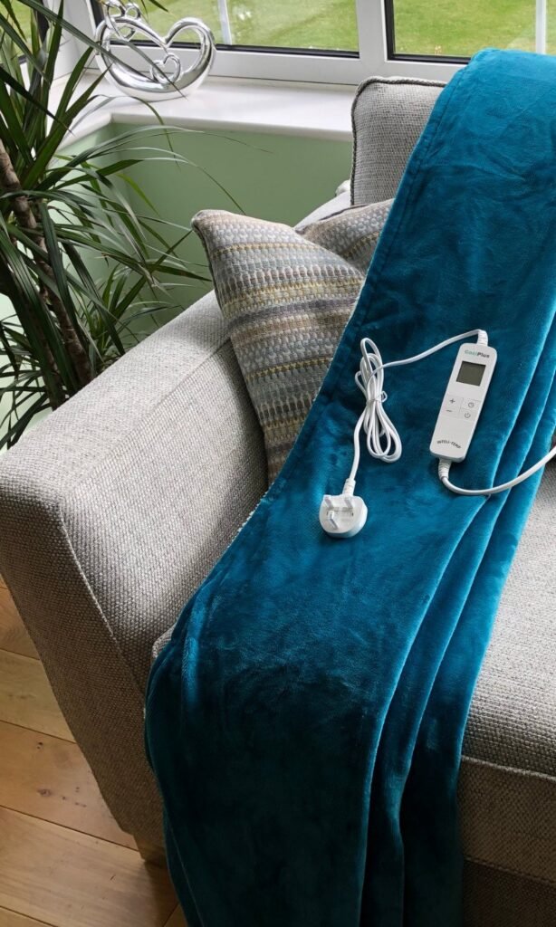 CoziPlus Premium heated throw in teal draped over a sofa